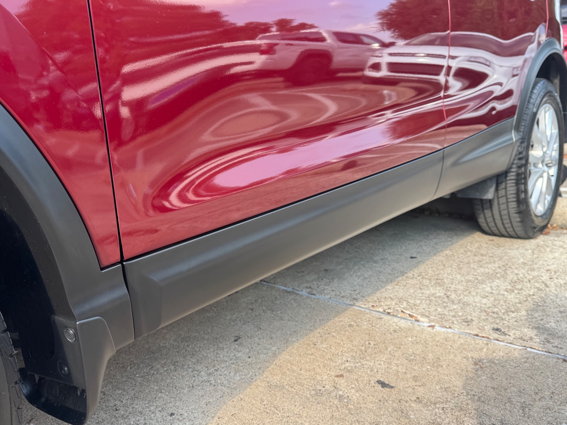 After photo of rocker panel cladding restored to natural black on red SUV